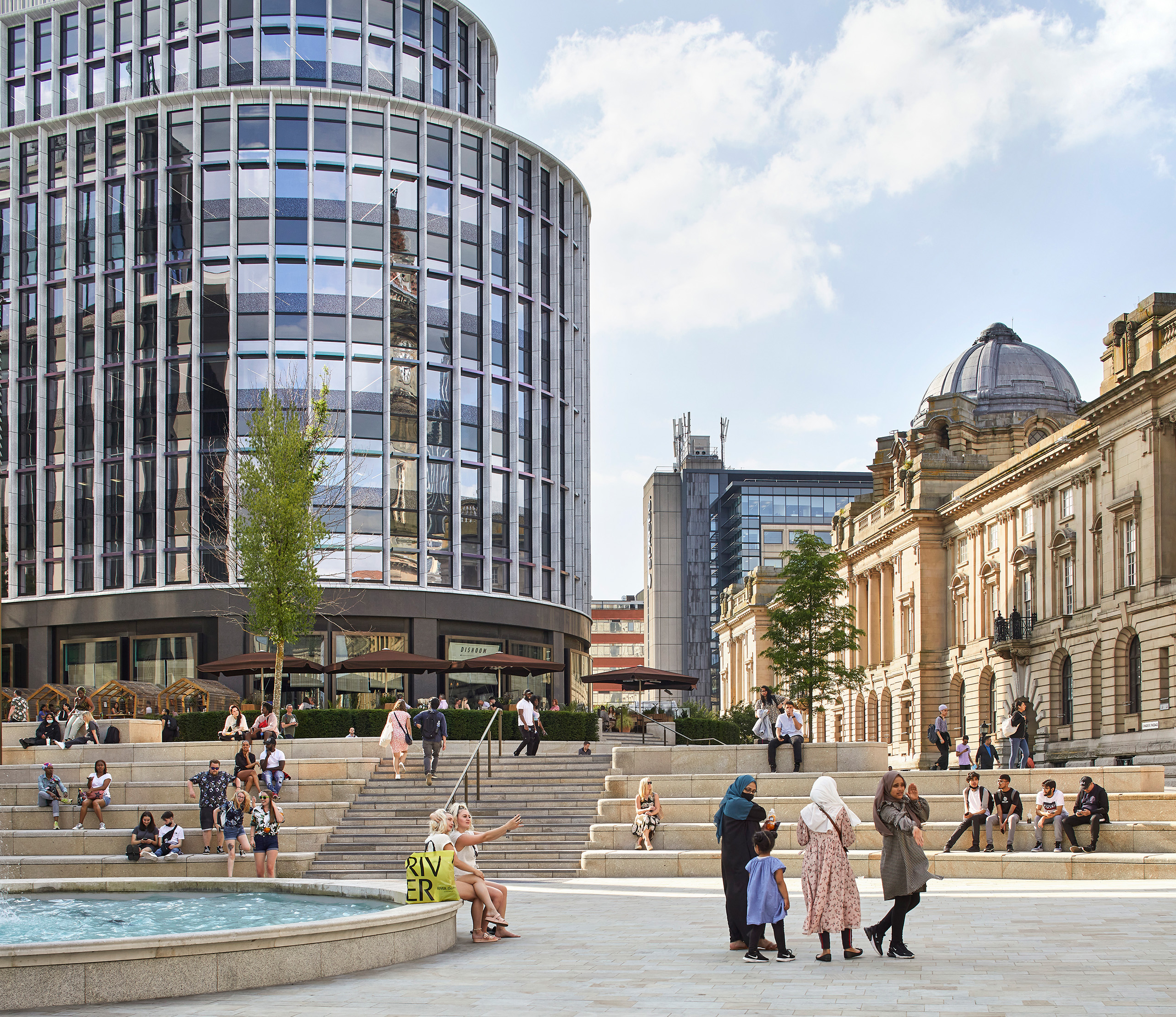 People chatting and having their lunch on the steps around the fountain at Chamberlain Square.