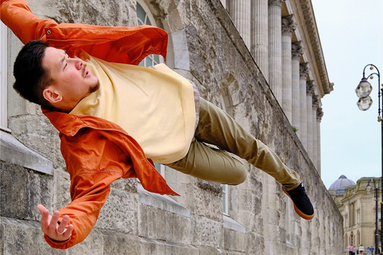 A man jumps to the side, his body fully horizontal, in front of the Town Hall in Birmingham.