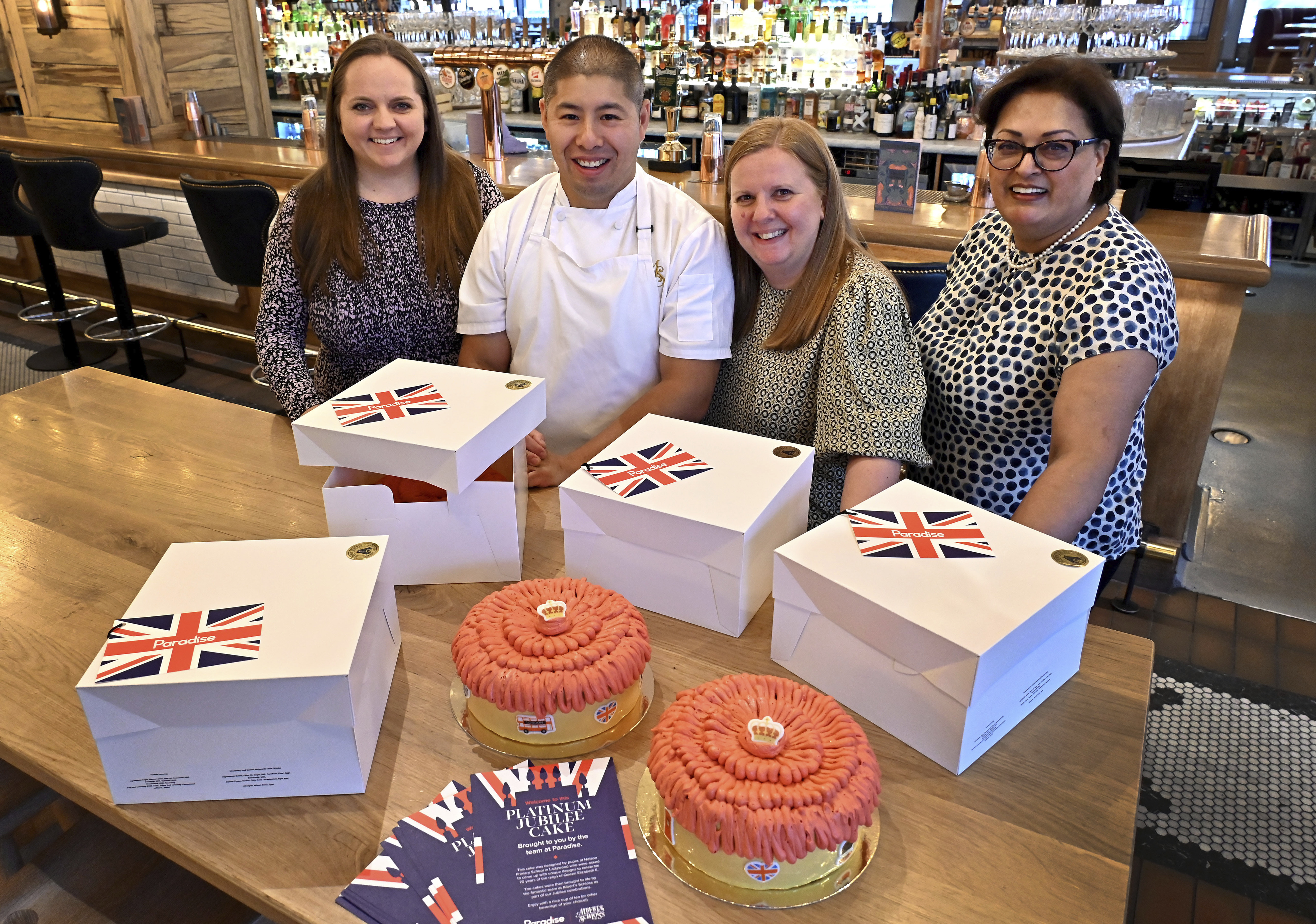 A group of people standing being boxed decorated cakes.