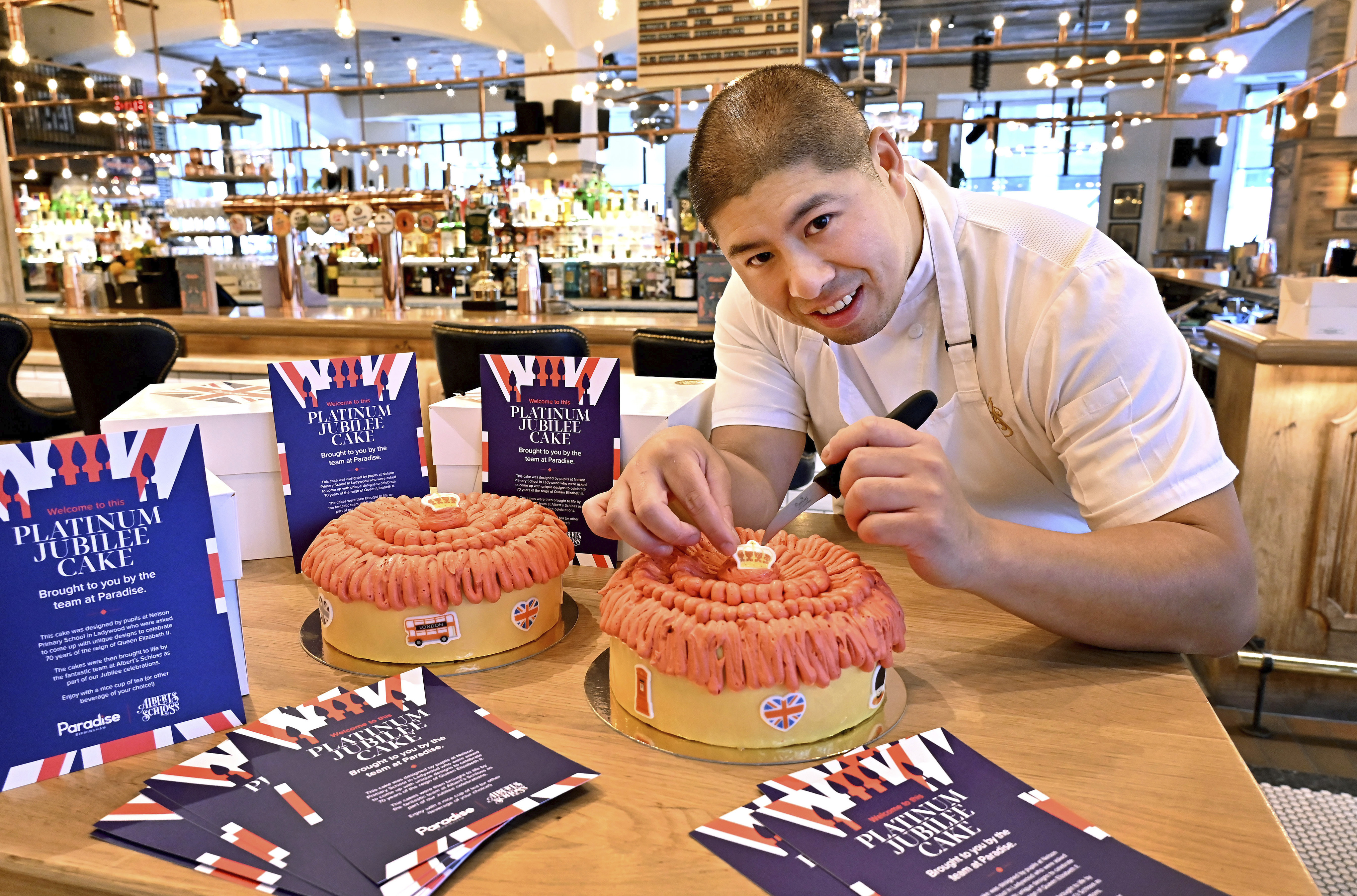 Pastry chef adding finishing touches to a Jubilee cake with decorative icing.