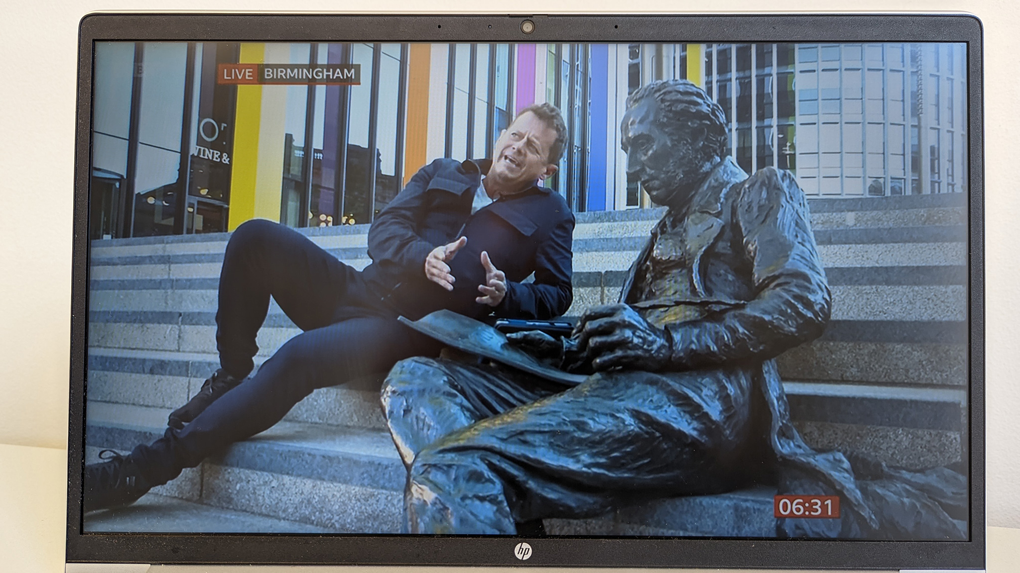 Mike Bushell, BBC reporter, sitting next to Thomas Attwood's statue in Chamberlain Square.