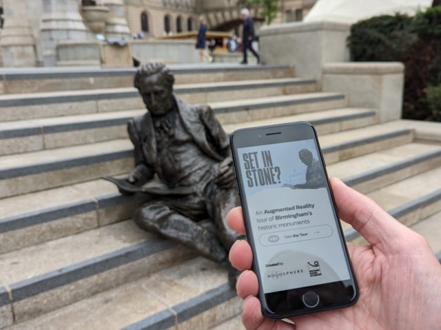 Someone using a mobile phone with augmented reality to find out more about the statues in Chamberlain Square, Paradise.